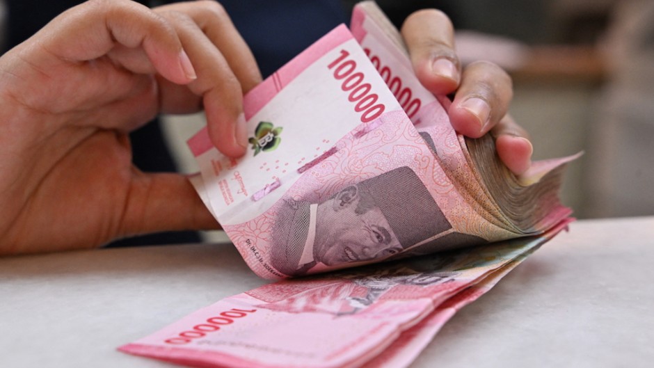 A clerk poses with Indonesian rupiah banknotes at a money changer in Jakarta. AFP/Adek Berry