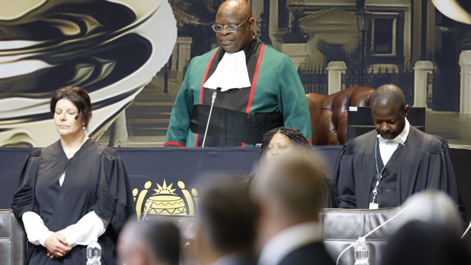 Chief Justice of South Africa Raymond Zondo (C) stands as he arrives at the first sitting of the New South African Parliament in Cape Town on June 14, 2024.