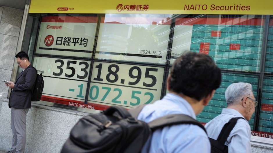 People walk in front of an electronic quotation board displaying the Nikkei index on the Tokyo Stock Exchange. AFP/Kazuhiro Nogi