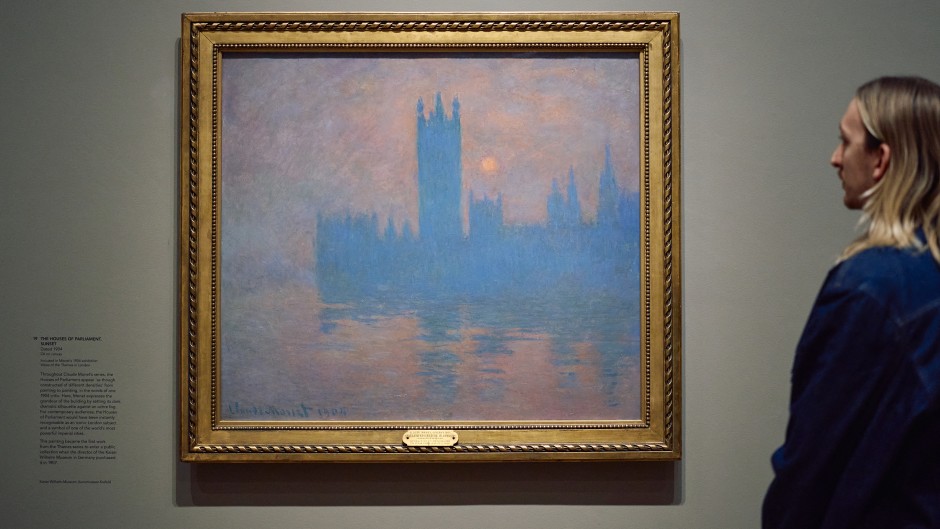 A gallery assistant studies a work by the french impressionist painter Claude Monet. AFP/Benjamin Cremel.jpg