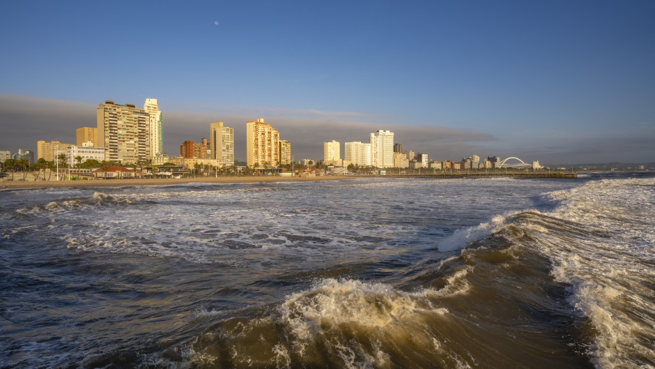 File: View of promenade, beach and hotels from pier in Indian Ocean at sunrise, Durban, KwaZulu-Natal Province, South Africa, Africa.