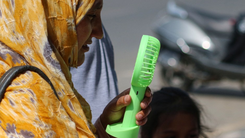 A woman is cooling off herself with a battery fan on a hot summer day in Srinagar. Firdous Nazir/NurPhoto via AFP