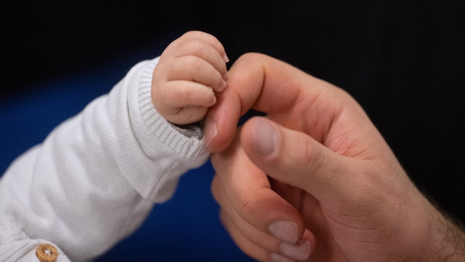 File: A father touches his child's hand during an infant handling course. Marijan Murat/dpa via AFP