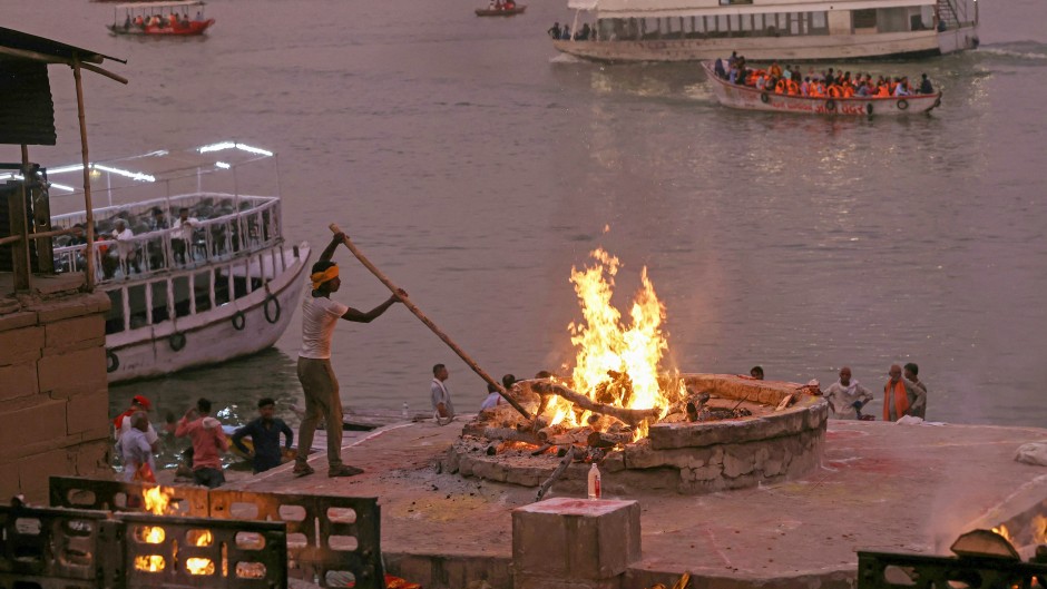 File: A cremator of the Dom community burns a funeral pyre at Harishchandra Ghat along the banks of river Ganges in Varanasi. AFP/Niharika Kulkarni