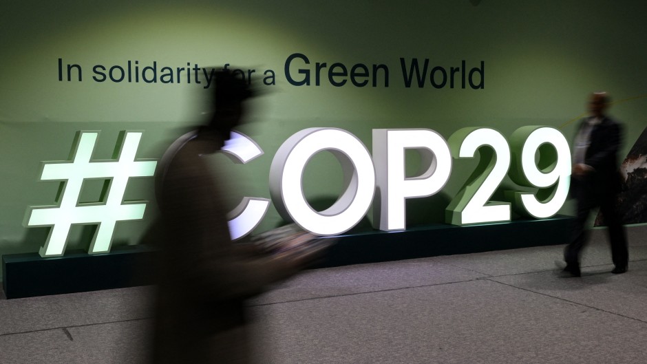 Attendees walk past the COP29 logo in Baku. AFP/Stringer