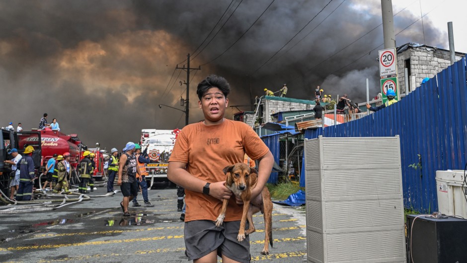 A man carries a dog during a fire at Tondo in Manila. AFP/Jam Sta Rosa