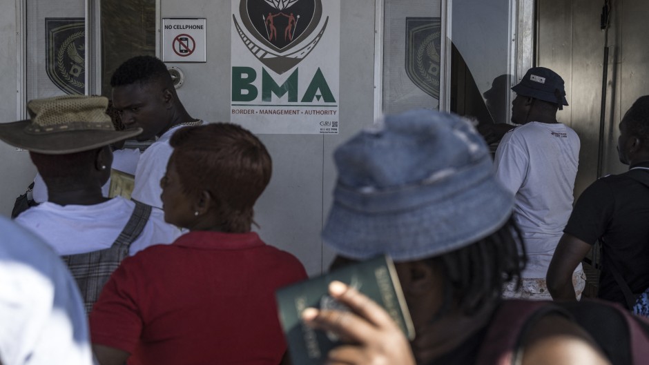 Zimbabwean migrants wishing to enter South Africa queue at a passport check before the immigration offices at the Beitbridge crossing. AFP/Marco Longari