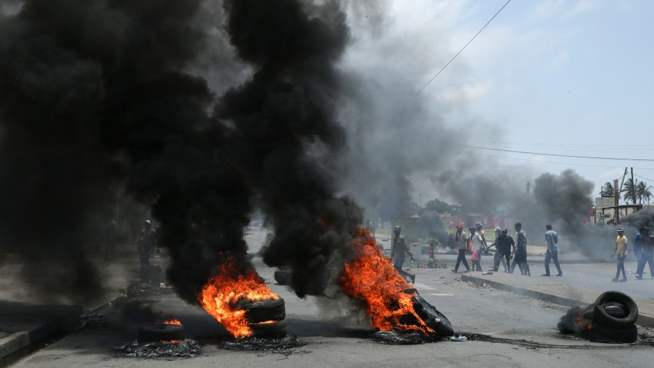 Protesters walk pass burning tires during a demonstration against the government in Maputo. AFP/Amilton Neves