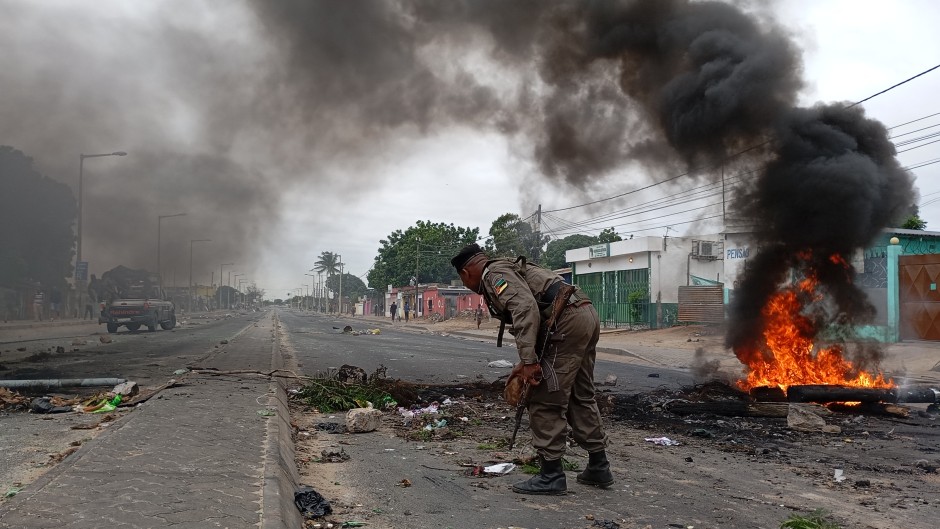 Mozambican security forces are seen next to a burning barricade in Maputo on December 24, 2024.