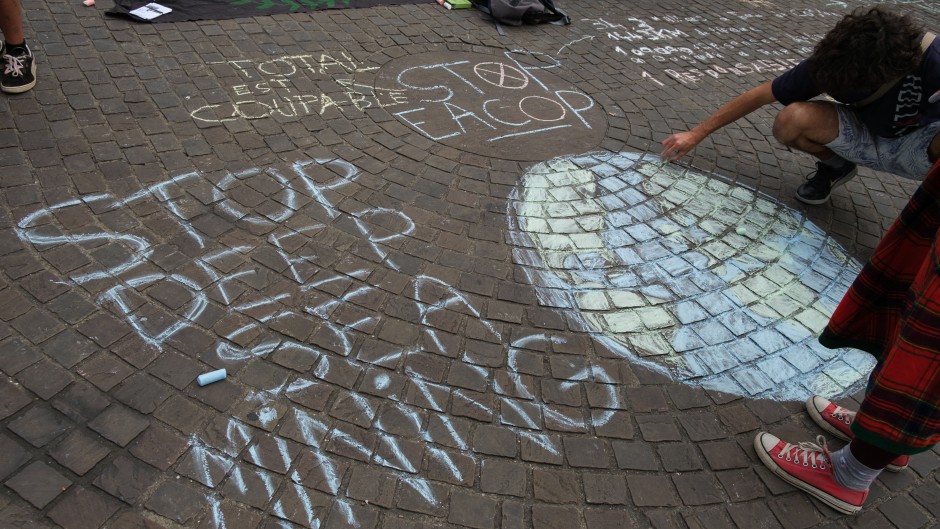 A person draws a message on a pavement calling for a stop to deep sea mining. Maylis Rolland/Hans Lucas via AFP