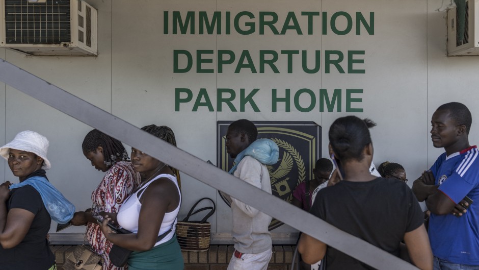 File: Zimbabwean migrants wishing to enter South Africa queue at a passport check before the immigration offices at the Beitbridge crossing. AFP/Marco Longari