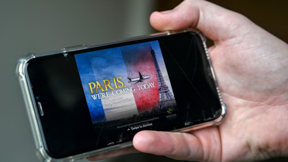 A man looks at an advert of the Pakistan International Airlines (PIA) plane flying at the Eiffel Tower. AFP/Farooq Naeem