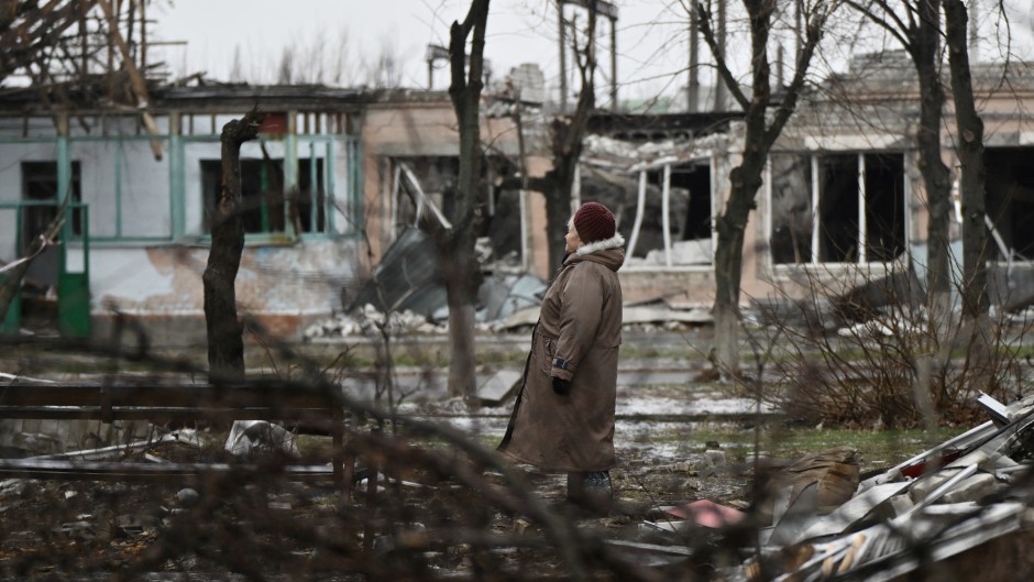 A woman stands among debris of her heavily damaged residential building in the town of Lyman. AFP/Genya Savilov