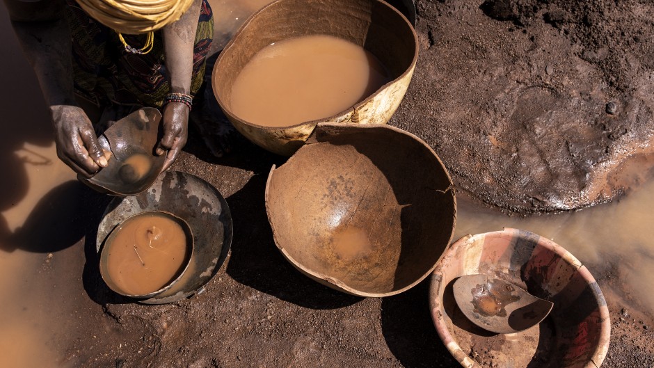 File: An artisanal miner pans for gold at a disused mine. AFP/John Wessels