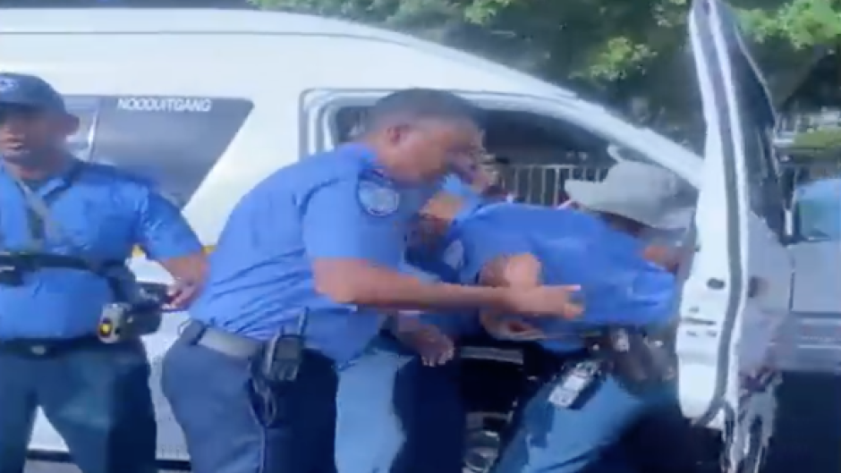 Cape Town Metro Police officers wrestling with a minibus taxi driver.