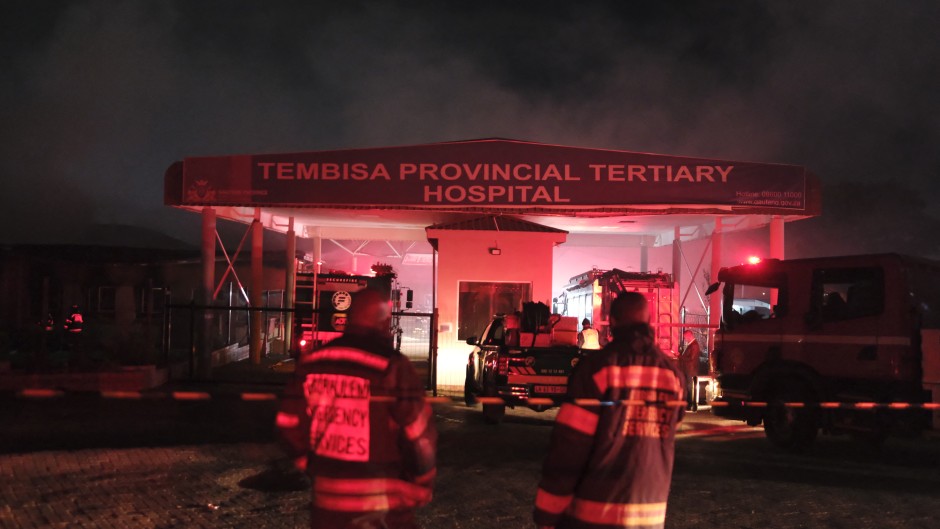 Firefighters stand outside the gate of the Tembisa Hospital after a fire broke out at the hospital’s accident and emergency unit. AFp/Emmanuel Croset