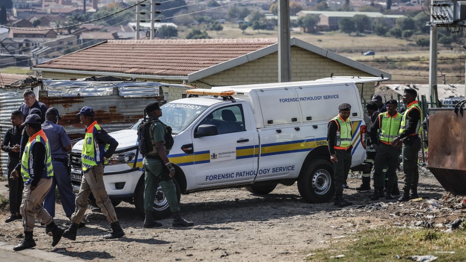 South African Police Service (SAPS) members and Gauteng Crime Prevention Wardens gather near the Forensic Pathology vehicle carrying the body of a person who died during a protest at Diepkloof Hostel in Soweto on May 19, 2025. 