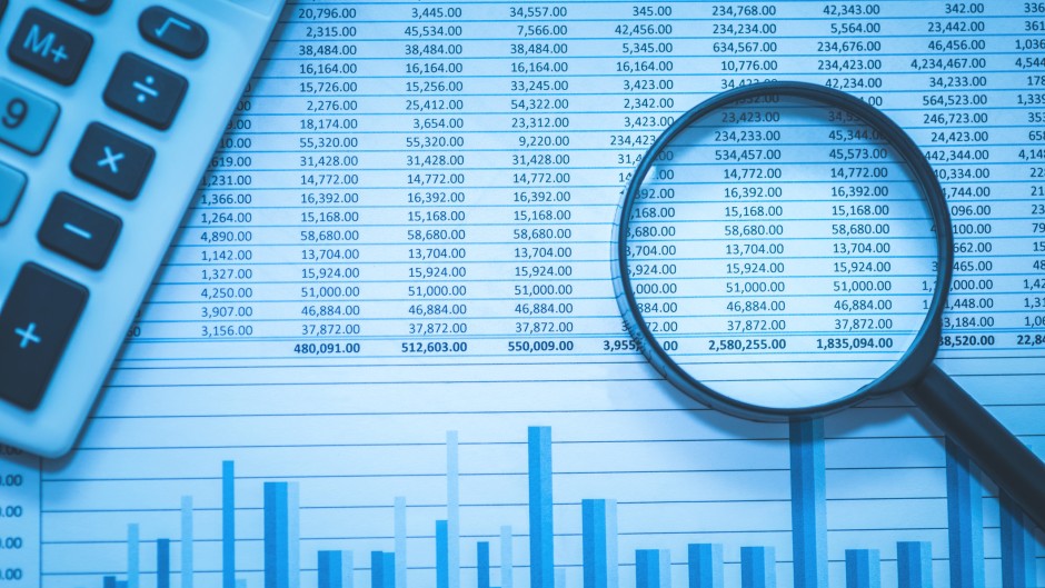File: Spreadsheet bank accounts accounting with calculator and magnifying glass. GettyImages/echoevg