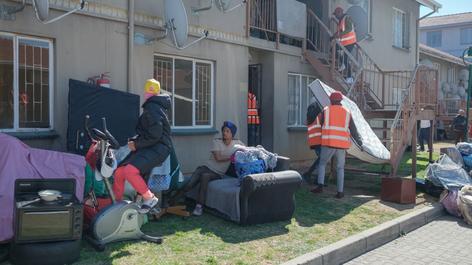 Residents carry their belongings as members of an eviction company assist the sheriff to evict them from an apartment building in Ekurhuleni on 12 August 2025.