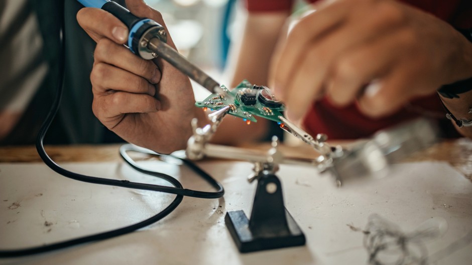 File: Students with soldering electrical components. GettyImages/supersizer