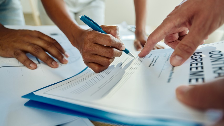 File: A person signing a contract agreement. GettyImages/skynesher