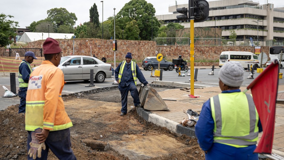 Road maintenance workers gather in a street under renovation in Braamfontein, Johannesburg, on November 7, 2025.