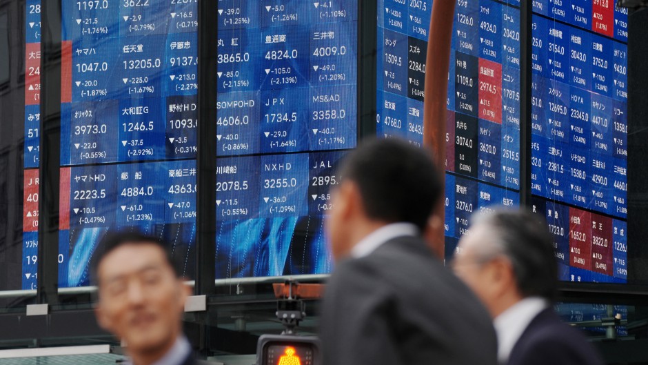 Pedestrians stand in front of an electronic quotation board displaying the Nikkei 225 stock prices on the Tokyo Stock Exchange. AFP/Kazuhiro Nogi