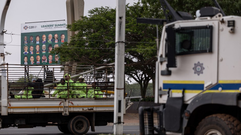 A truck transporting workers drives past a SAPS armoured vehicle outside the Nasrec Expo Centre in Johannesburg. AFP/Emmanuel Croset 