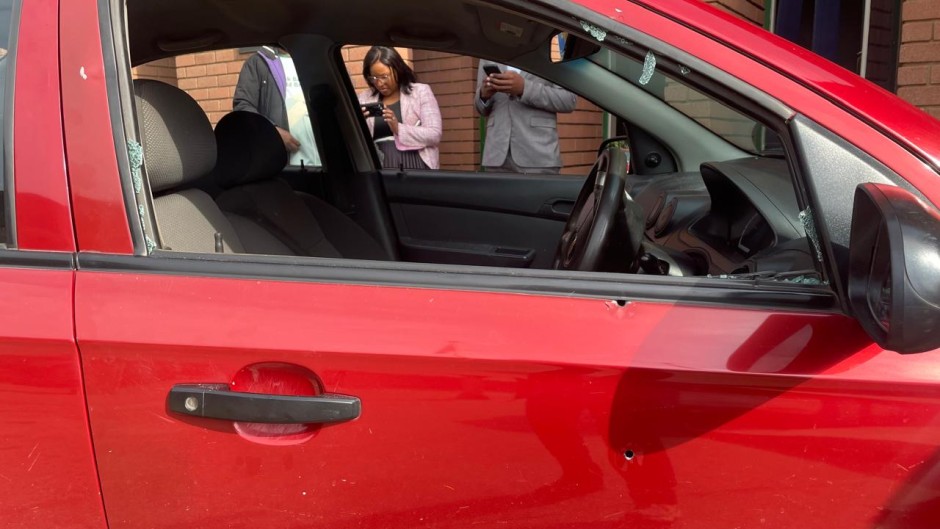 A red Chevrolet Aveo sedan, with a broken window.