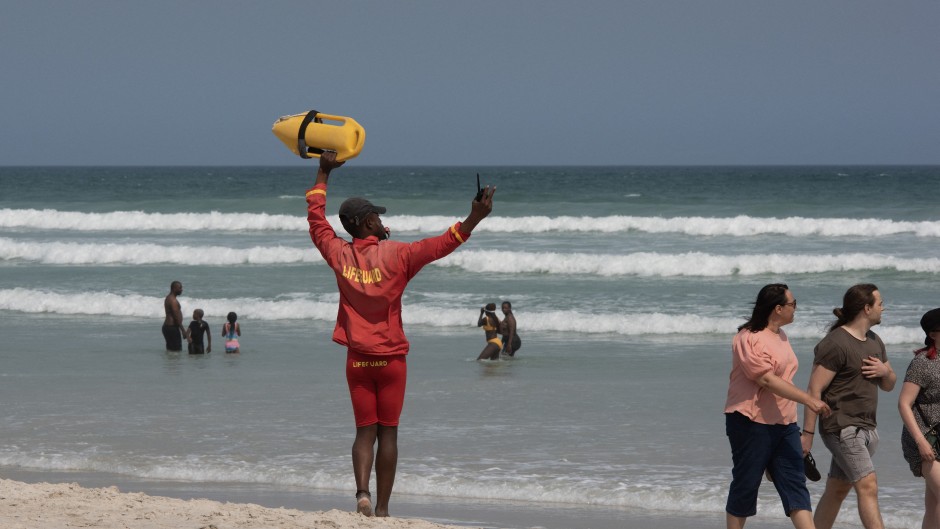A lifeguard directs people to move into the swimming zone. AFP/Rodger Bosch