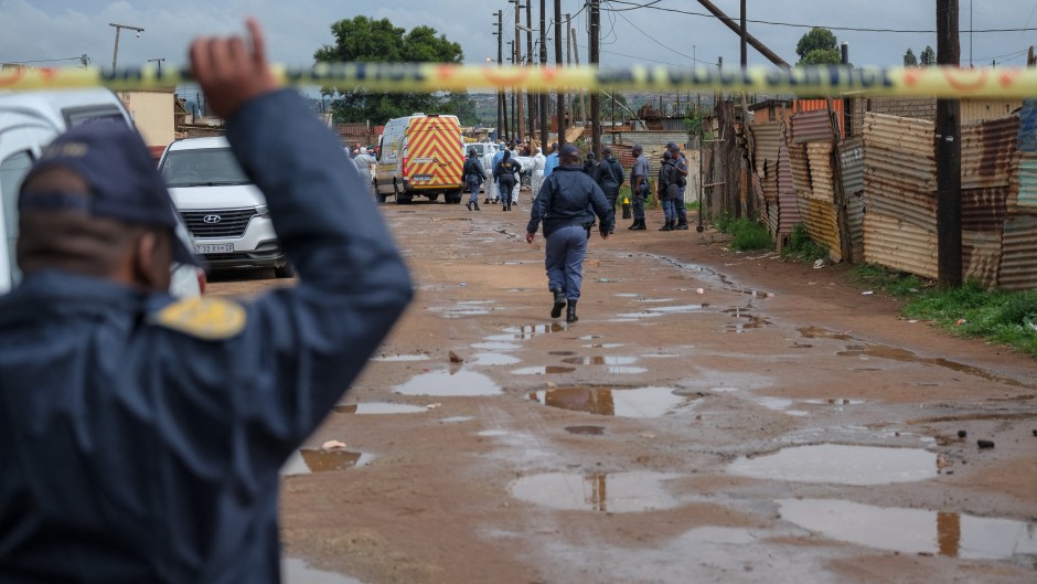 Police officers stand at the scene of an attack at a tavern in Bekkersdal. AFP/Emmanuel Croset