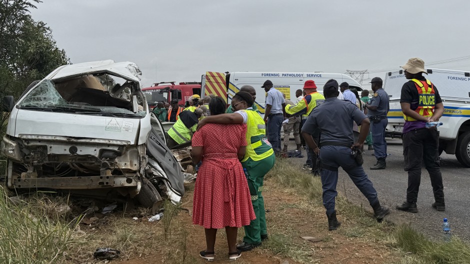 A rescue worker (2nd L) comforts a woman (L) at the scene of the Vaal accident. AFP/John Mkhize