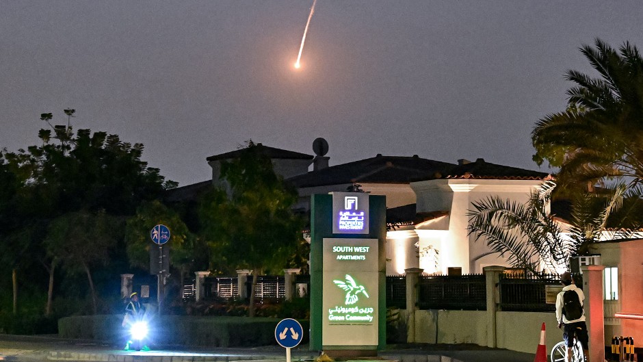 A cyclist watches as a projectile falls over Dubai. AFP