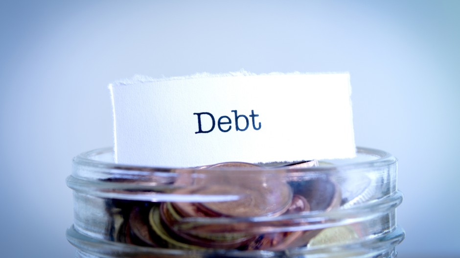 A  close-up shot of the word Debt on a jar of coins. GettyImages/Synergee