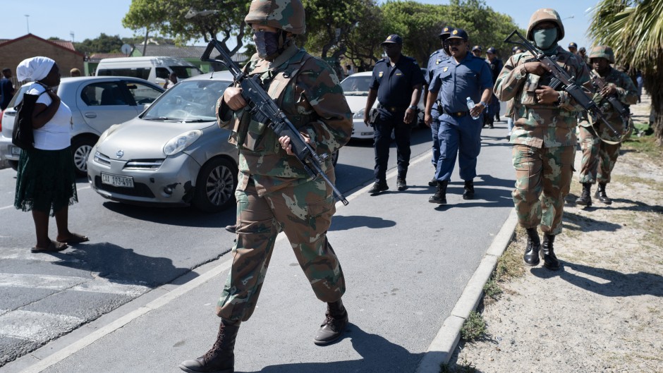 South African National Defence Force (SANDF) soldiers walk with South African Police Service (SAPS) officers in Mfuleni township in Cape Town on March 31, 2026.