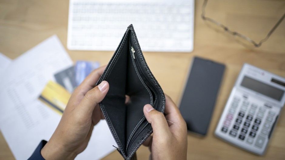 File: A person looking at an empty wallet with a calculator and credit cards. GettyImages/seksan Mongkhonkhamsao