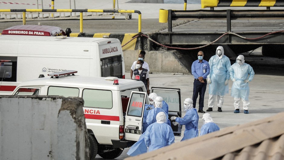 Health personnel returning from the cruise ship MV Hondius, are seen at the port of Praia, the capital of Cape Verde, as individuals wearing hazmat suits are helped into an ambulance on May 6, 2026.