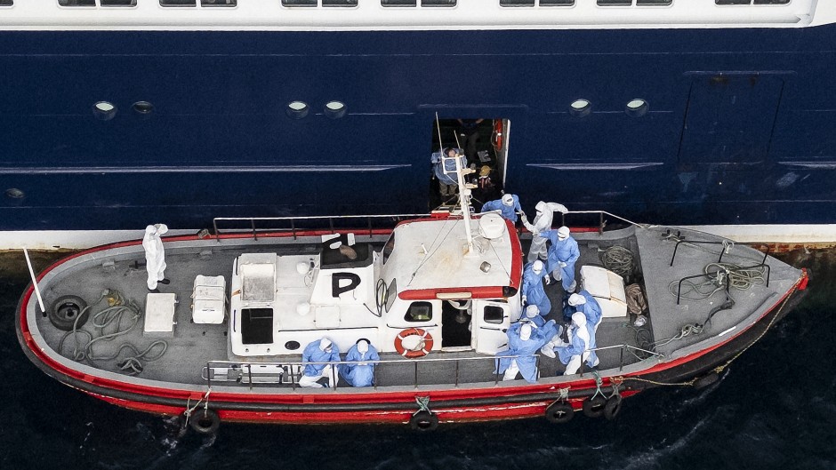 This aerial view shows health personnel assisting patients onto a boat from the cruise ship MV Hondius, while stationary off the port of Praia, the capital of Cape Verde, on May 6, 2026.