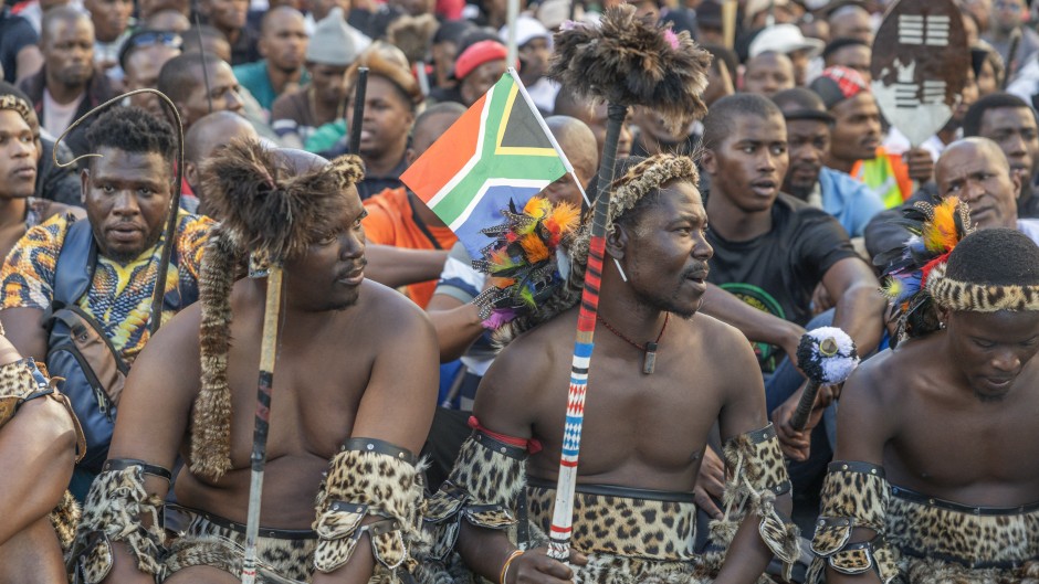 A South African flag is seen in a protester's head gear as he gathers with other protesters during a protest march against undocumented migrants in Durban on May 6, 2026.