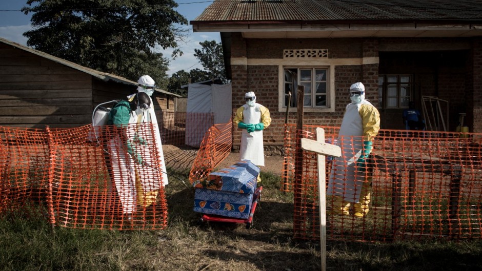 File: Medical workers disinfect the coffin of a deceased unconfirmed Ebola patient inside an Ebola Treatment Centre. AFP/John Wessels