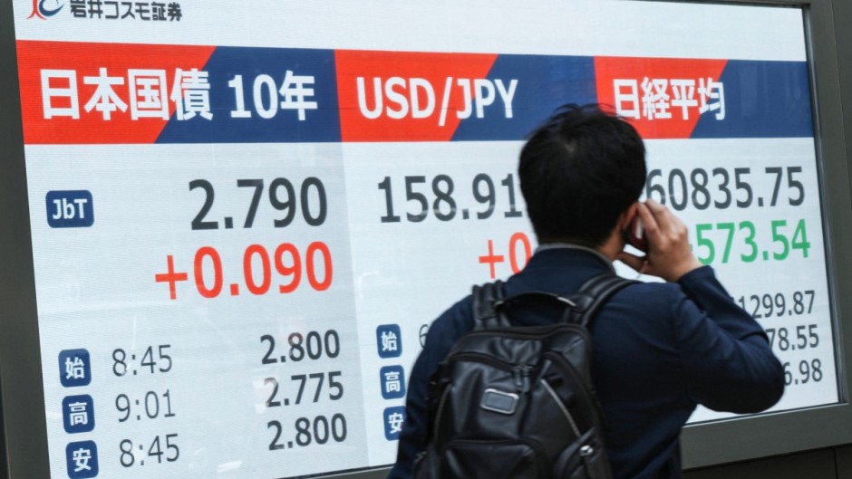 A man walks past an electronic quotation board displaying 10-year Japanese government bonds. AFP/Kazuhiro Nogi
