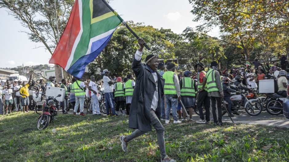 A “March and March” supporter waves the South African flag during a protest march in Durban on May 20, 2026.