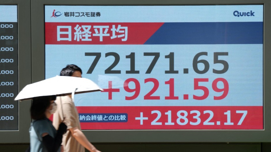 Pedestrians walk past an electronic quotation board displaying the Nikkei Stock Average on the Tokyo Stock Exchange in Tokyo. AFP