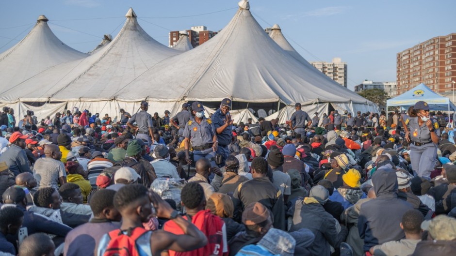 Police officers keep order as hundreds of newly displaced foreign nationals take refuge at the old Durban Drive Inn in Durban. AFP/Rajesh Jantilal