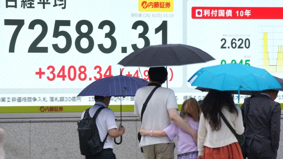 Pedestrians walk past an electronic quotation board displaying the Nikkei Stock Average. AFP/Kazuhiro Nogi