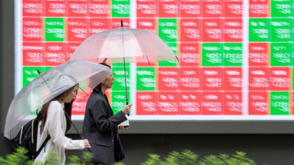 Pedestrians walk past an electronic quotation board displaying the Nikkei 225 stock prices. AFP/Kazuhiro Nogi