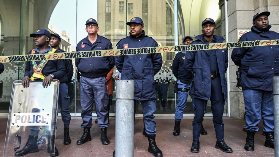 Members of the South African Police Service (SAPS) stand in formation as they monitor a demonstration by the "March and March" and Operation Dudula movements.  AFP/Rodger Bosch