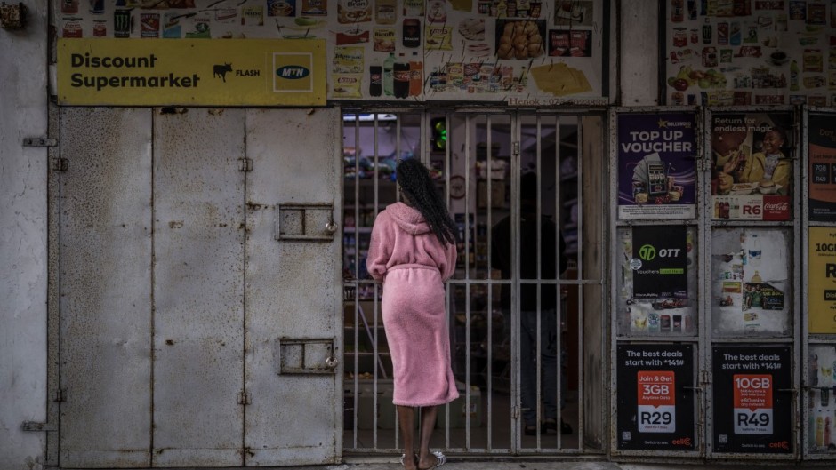 File: A resident wearing a bathrobe buys last minutes goods from a half closed shop. AFP/Marco Longari