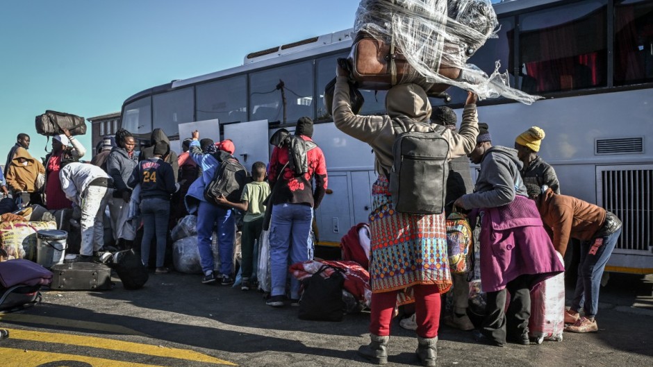 Zimbabwean nationals line up carrying their belongings as they wait to board a bus at a Department of Home Affairs Refugee Reception Centre while awaiting repatriation. AFP/Rodger Bosch