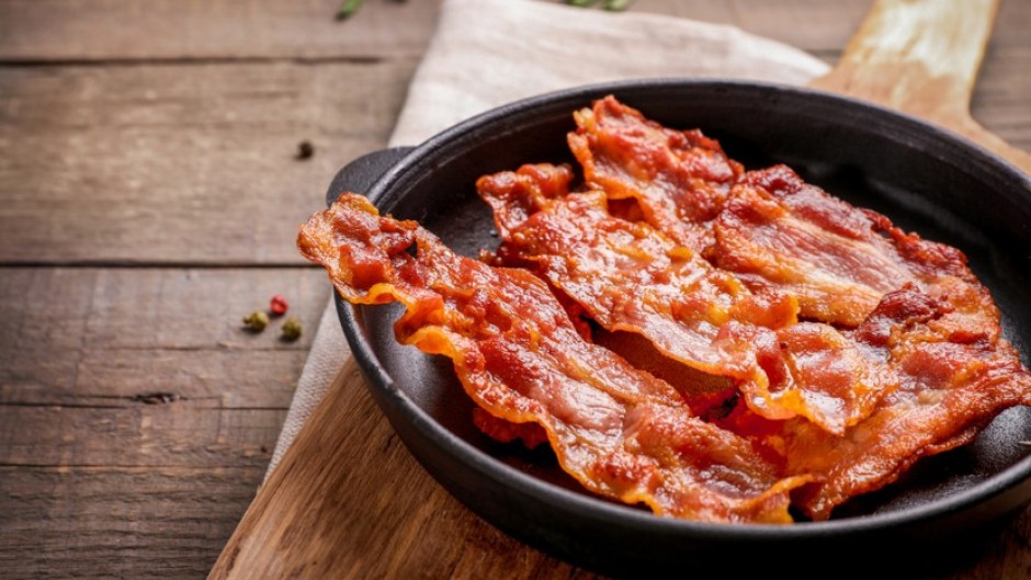 Hot fried crispy bacon slices in a skillet. GettyImages/LumenSt